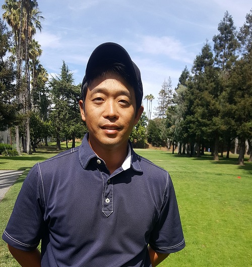 Headshot of man wearing blue polo, with a visor  on the golf course